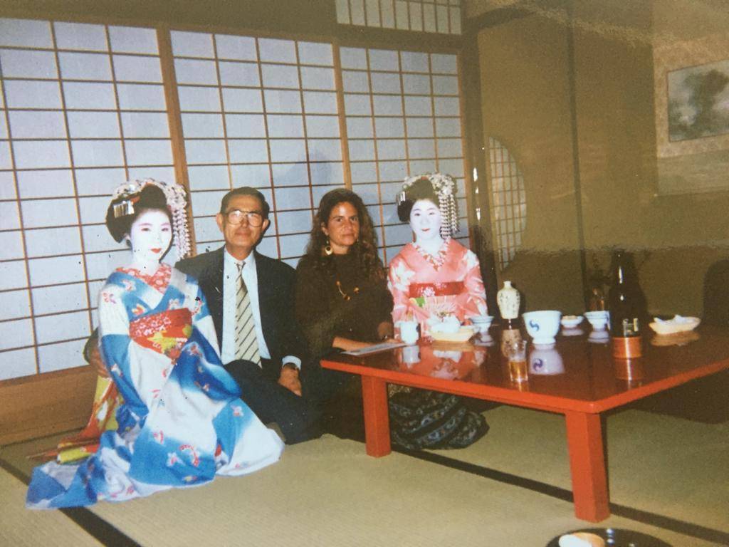 Erinnerungsfoto aus Japan: Bettina Flossmann mit zwei Maikos im Kimono und einem Gastgeber an einem niedrigen Tisch