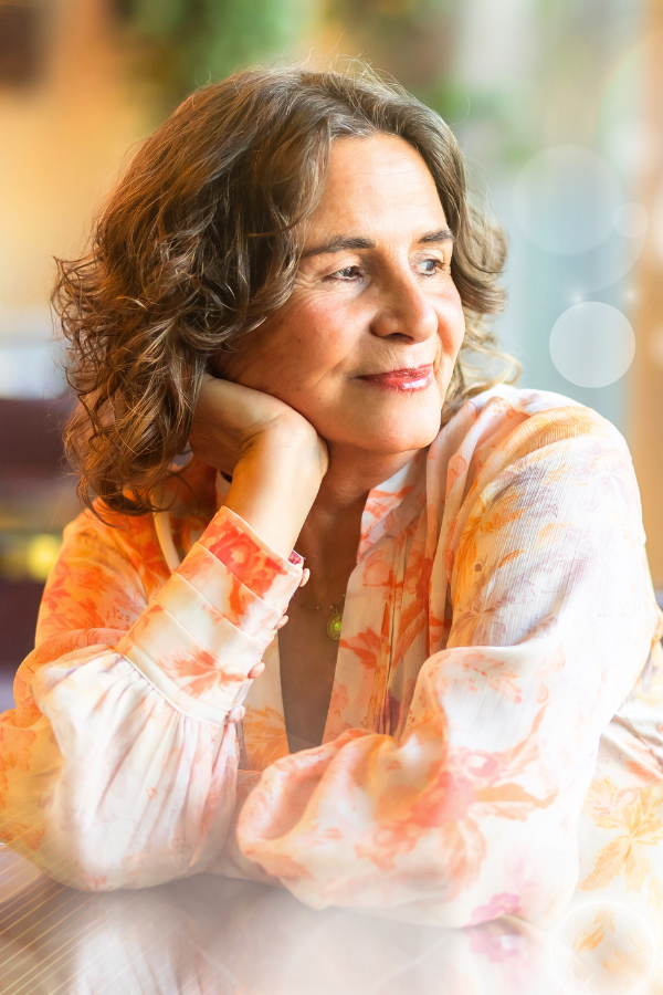 Bettina Flossmann, den Kopf in die Hand gestützt, schaut nachdenklich lächelnd zur Seite